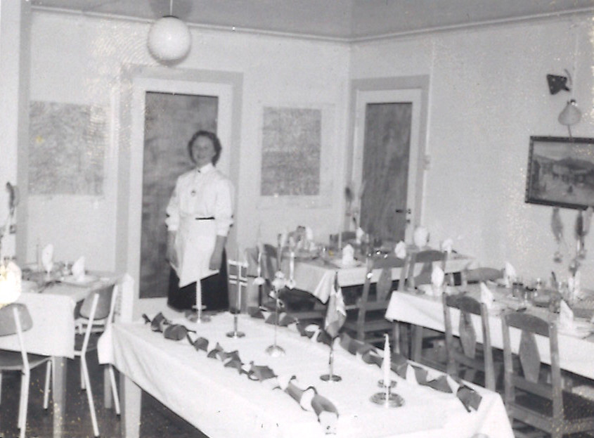 Gammelt bilde fra 1960-tallet av matsalen på Haugly. Bord dekket med hvite duker, bordflagg og servietter