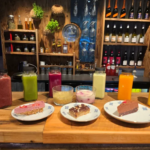 Disk med kaker og smoothies, hyller med flasker i bakgrunnen