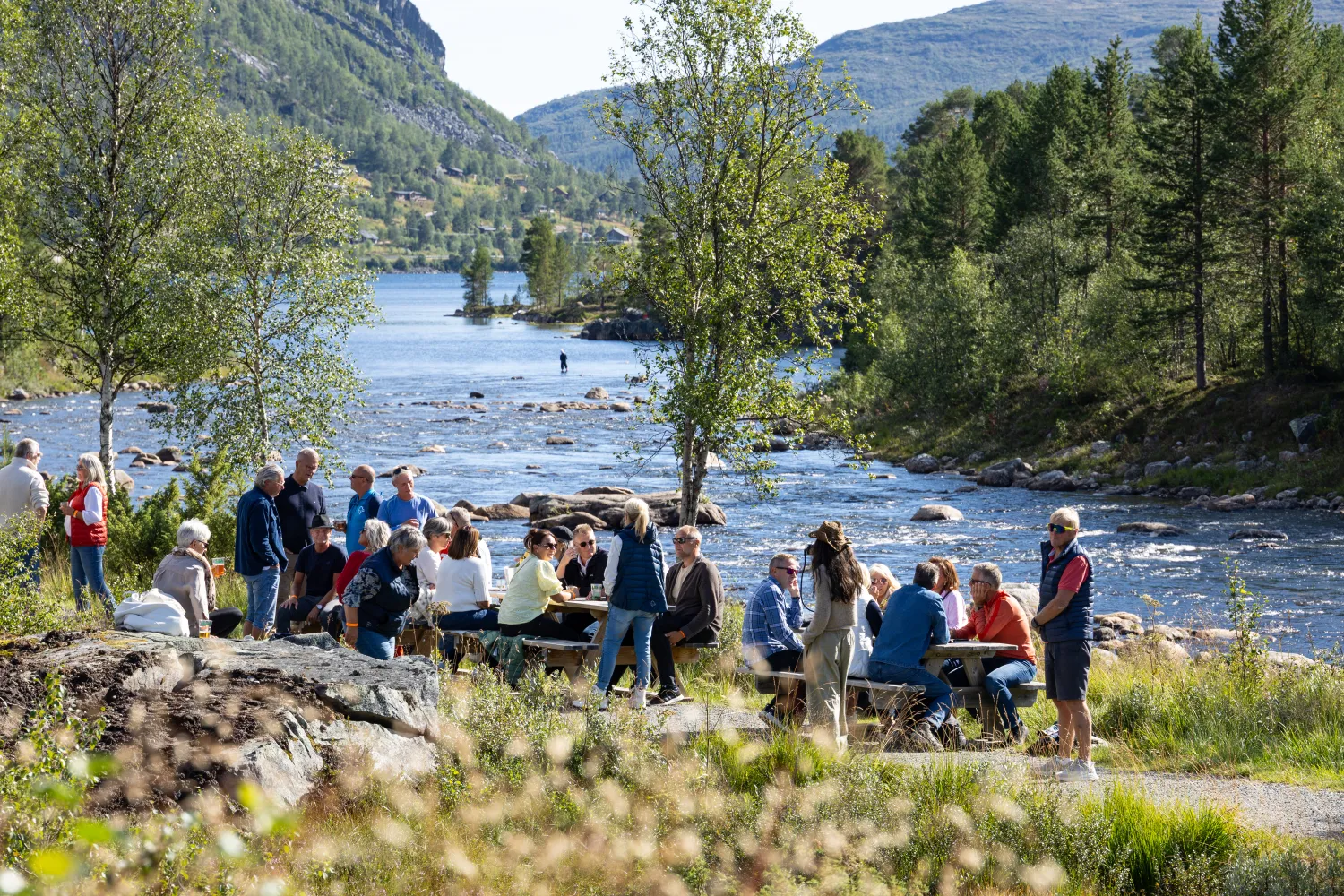 Folk koser seg på benker langs Otra ved Hovdestøylen
