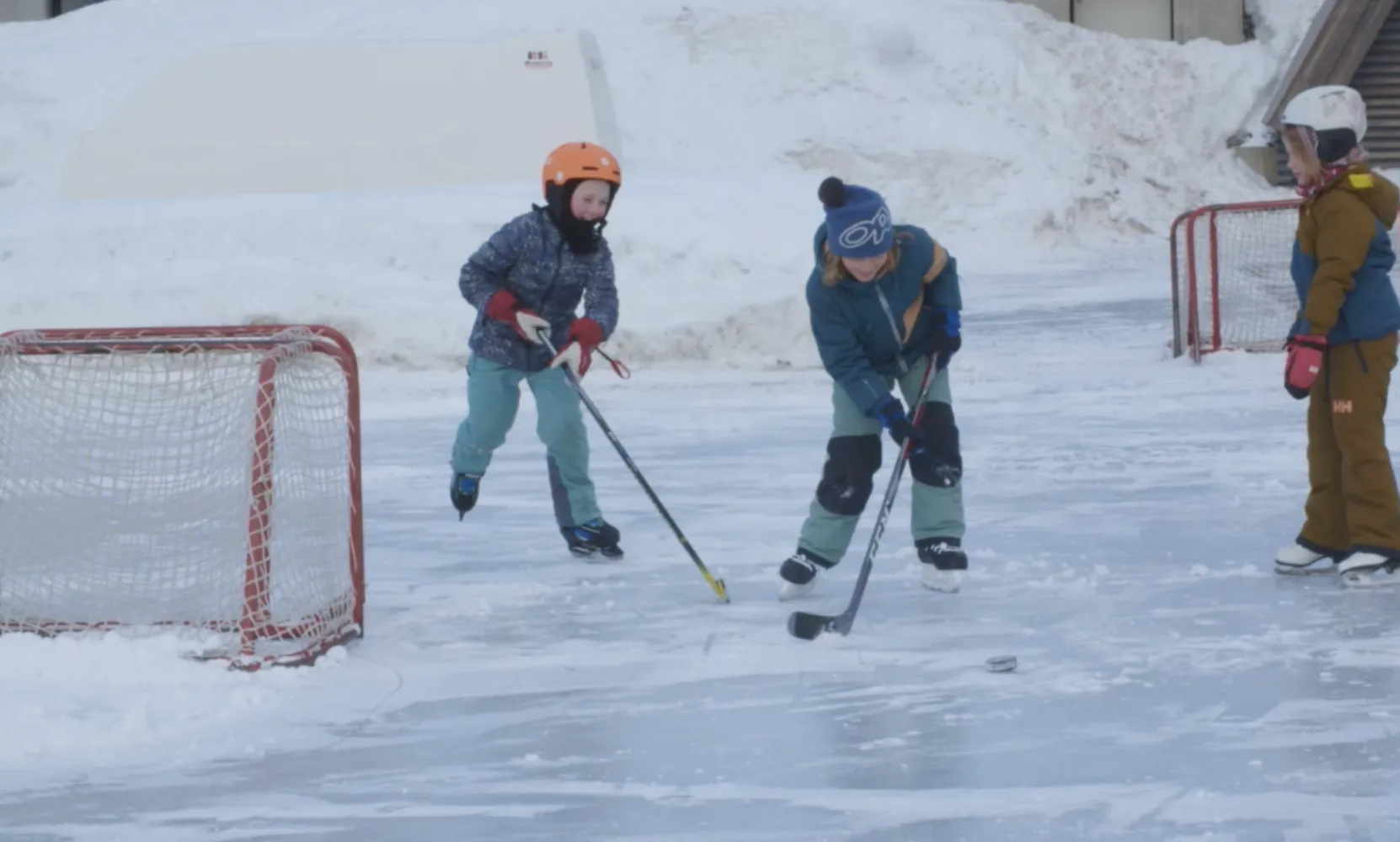 3 barn på isen som spiller ishockey