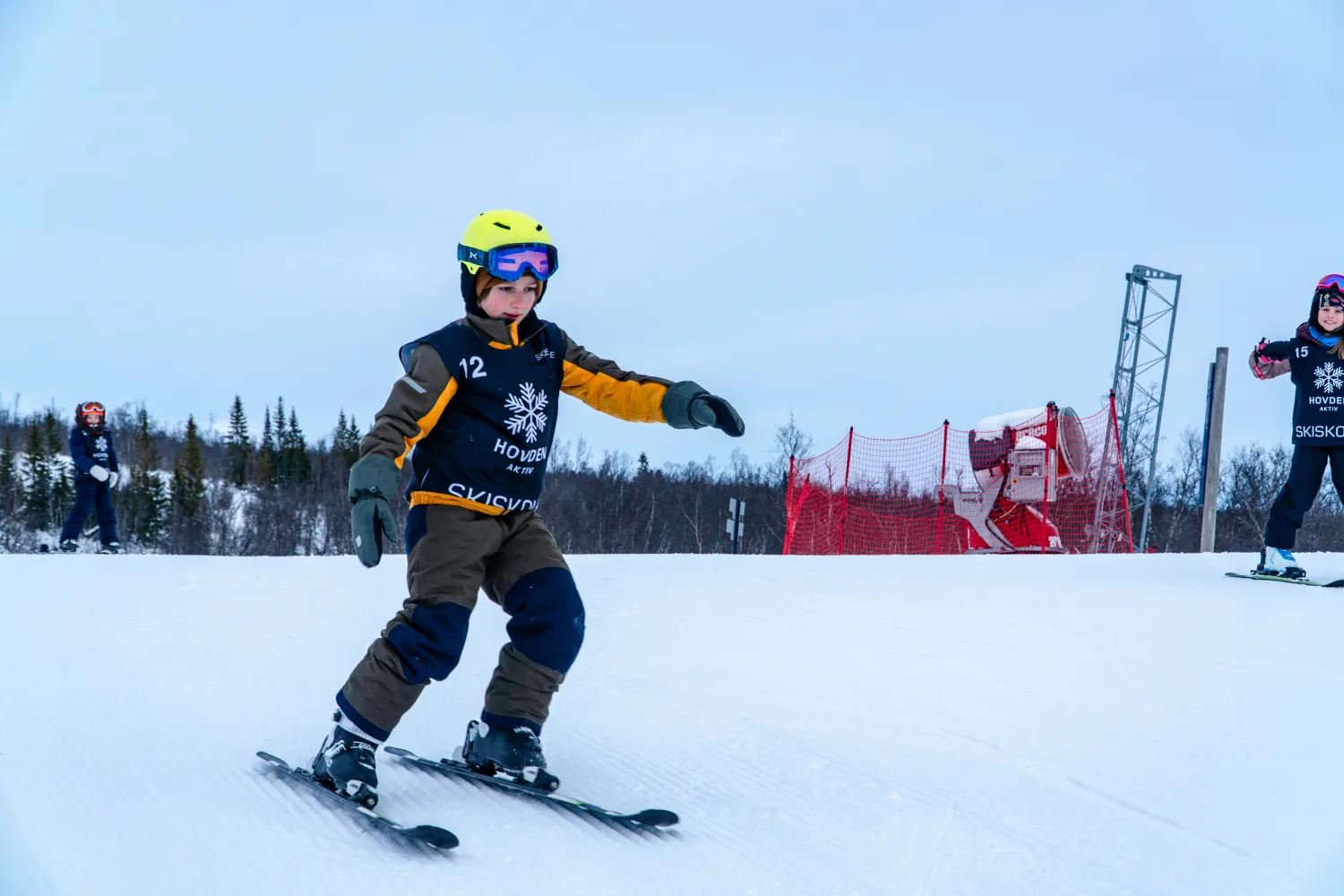 Barn på ski under skiskoleundervisning hos Hovden Aktiv, med et barn i forgrunnen som øver på å svinge.