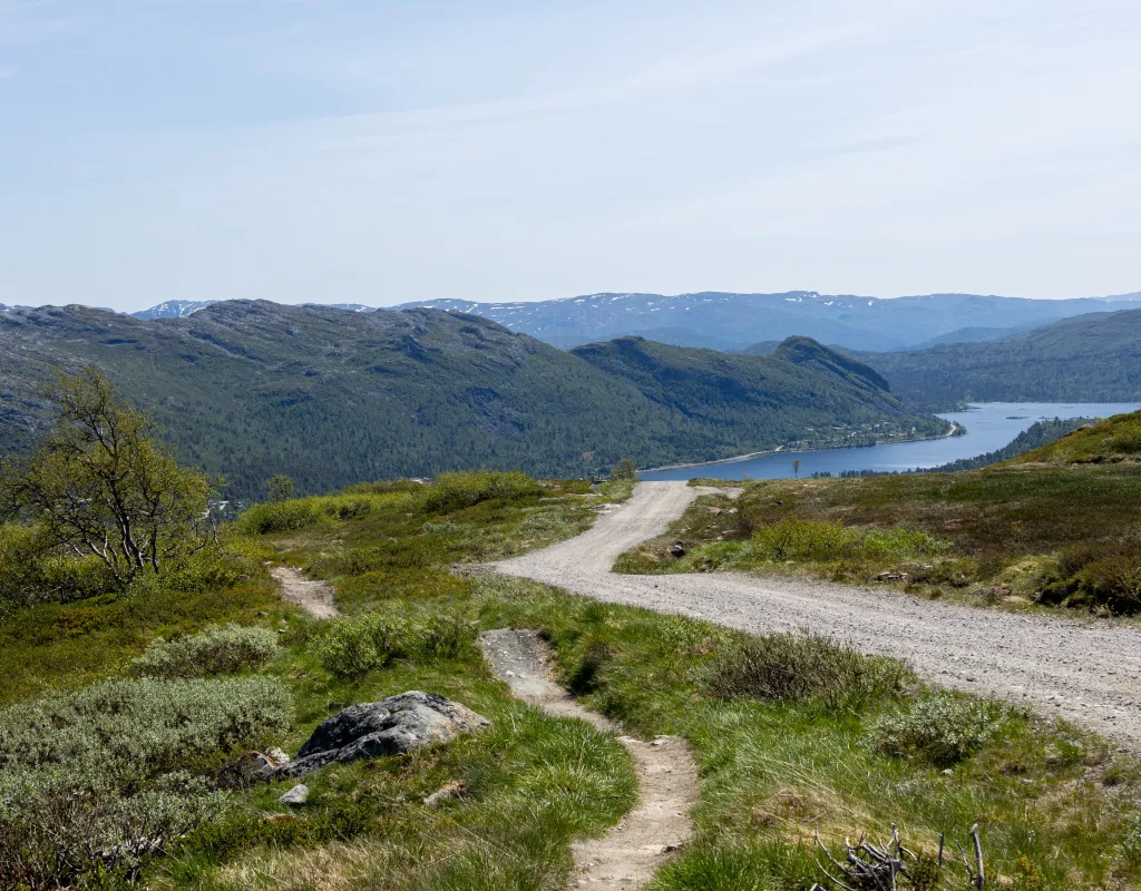 Sommerbilde fra anleggsvei i alpinsenter med utsikt over fjell og innsjø